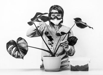 Portrait of woman with tropical plant monstera against white wall