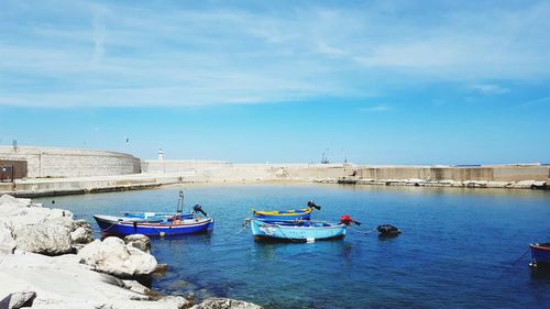 Boats moored on sea against blue sky