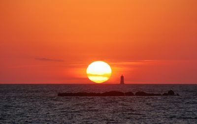 Scenic view of sunset sea against orange sky 