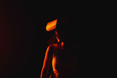 Man holding illuminated fire against black background