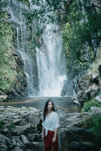 Rear view of woman standing against waterfall