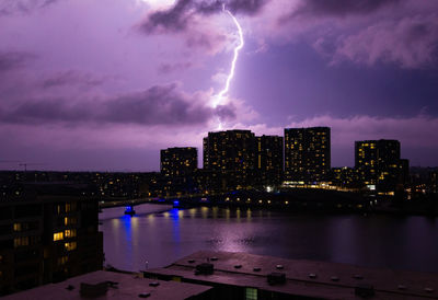 Lightning over illuminated buildings in city at night