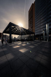 Illuminated street amidst buildings against sky during sunset