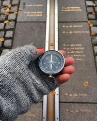 Cropped hand of woman holding compass over footpath