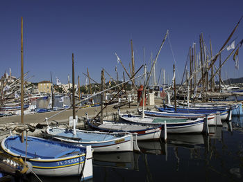 Sailboats moored at harbor against clear blue sky