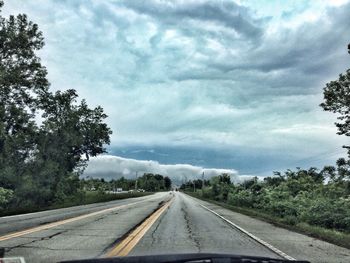 Country road against cloudy sky