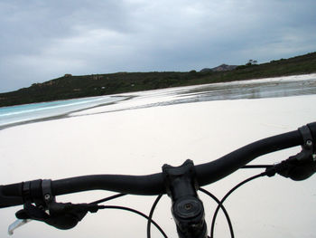 Bicycle on road by sea against sky