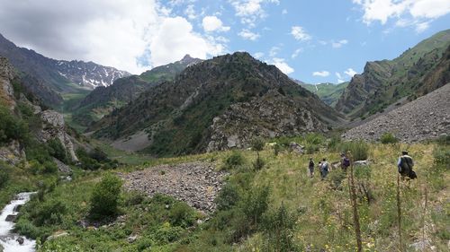 Hikers walking on landscape against mountains