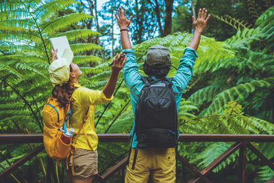 Rear view of men with arms raised against trees