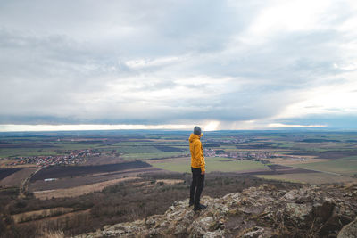 Rear view of man standing on mountain against sky