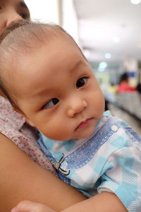 Close-up of baby boy with mother suffering from cross-eyed at hospital