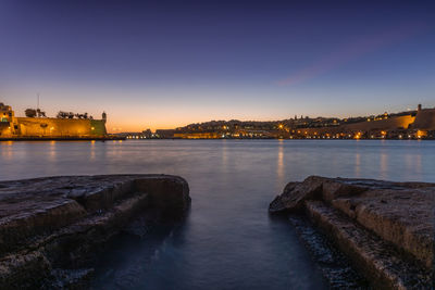 View of illuminated buildings by river at night