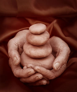 Cropped hands holding stacked pebbles