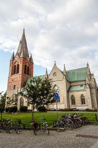 Bicycles in front of church against cloudy sky