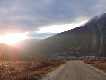 Road by mountains against sky