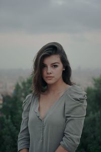 Portrait of beautiful young woman standing against sky