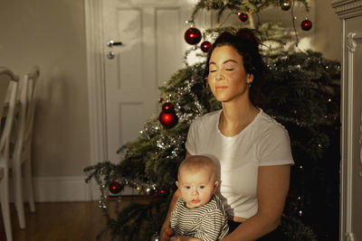 Mother with baby in front of christmas tree