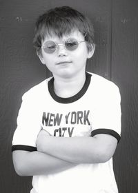 Portrait of boy wearing sunglasses standing against wall