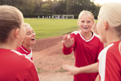 Happy female athletes standing against soccer field