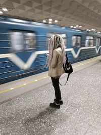 Woman with dreadlocks standing against train at railroad station