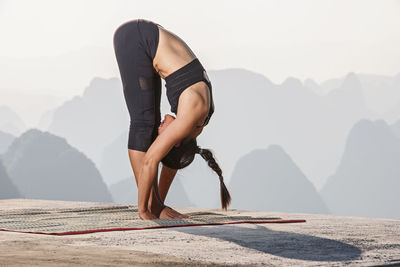 Beautiful woman practising yoga above the kast mountains of yangshuo