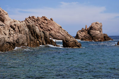 Rock formations in sea against sky