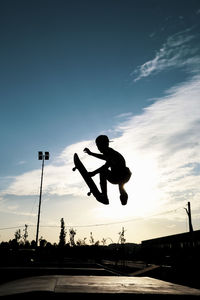 Silhouette man jumping against sky during sunset