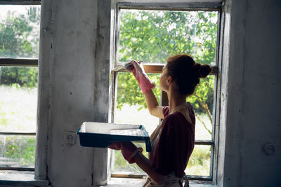 Side view of woman painting window