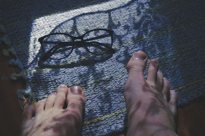 Low section of man with eyeglasses on floor