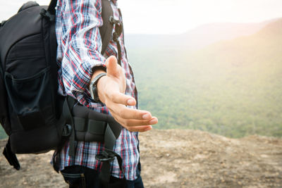 Midsection of teenage boy with backpack standing on mountain