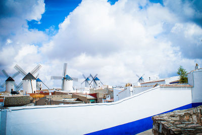 Buildings and windmills against cloudy sky