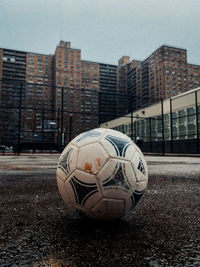 Soccer ball on field against buildings in city