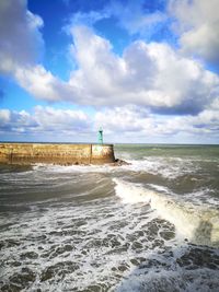 Lighthouse on beach by sea against sky