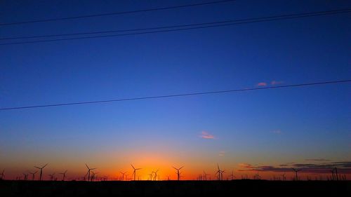 Low angle view of electricity pylon at sunset