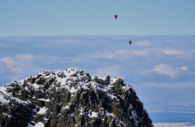 Hot air balloon flying over mountain against sky