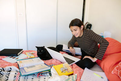 Middle school girl sits on her bed while on a zoom class meeting