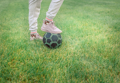 Cute little girl playing football with soccer ball on green lawn in backyard of house. 