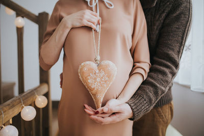 Midsection of woman holding heart shape