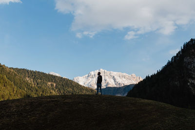 Man standing on hill amidst mountains against sky