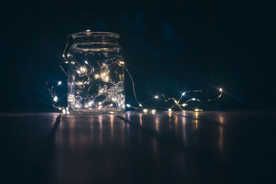 Close-up of illuminated glass jar on table