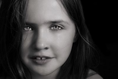 Close-up portrait of smiling girl over black background