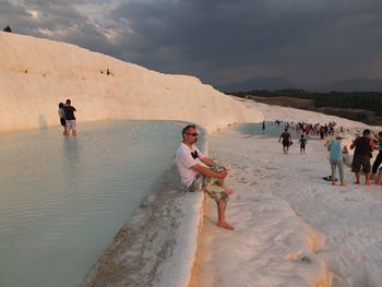 People at travertine pool against sky