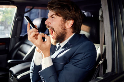 Businessman shouting on phone call in car