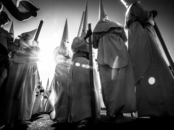 Low angle view of penitente people walking on road against sky