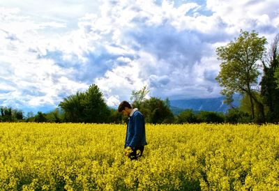 Rear view of man standing on field against sky