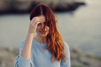 Portrait of smiling young woman standing against water