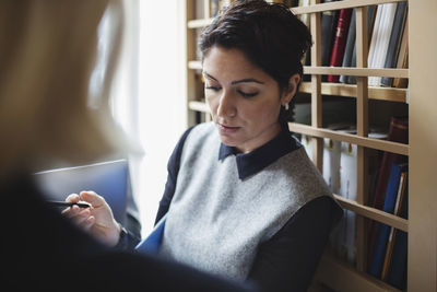 Young woman looking away while sitting on book