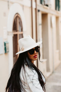 Young woman wearing hat standing in city