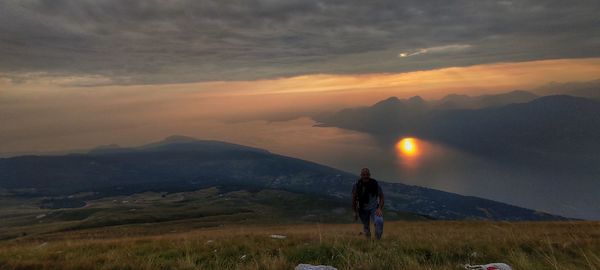 Man standing on mountain against sky during sunset