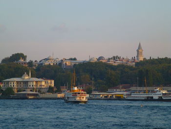 Boats in sea by buildings in istanbul against sky